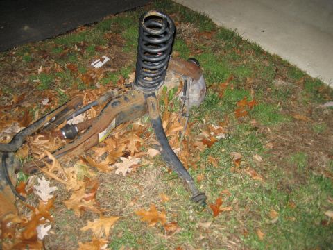 1996 Ford Bronco - A detached vehicle suspension system rests on the ground, surrounded by autumn foliage.