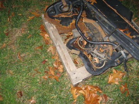 1996 Ford Bronco - Discarded vehicle components, heavily rusted, rest on a wooden pallet amidst autumn foliage.