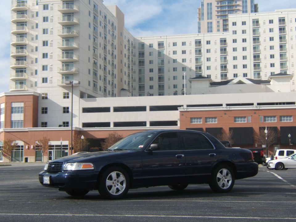 Dark blue sedan parked in a lot with buildings in the background