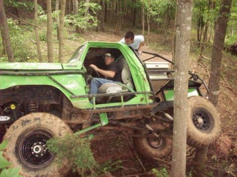1978 Ford Bronco - Modified off-road vehicle with a roll cage is being driven through a wooded area.