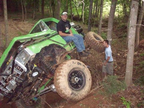 1978 Ford Bronco - This heavily modified off-road vehicle appears to be stuck in the mud on a wooded trail.