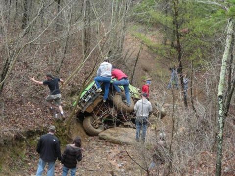 1978 Ford Bronco - An off-road vehicle is stuck on a muddy incline, with several people gathered around attempting to free it.