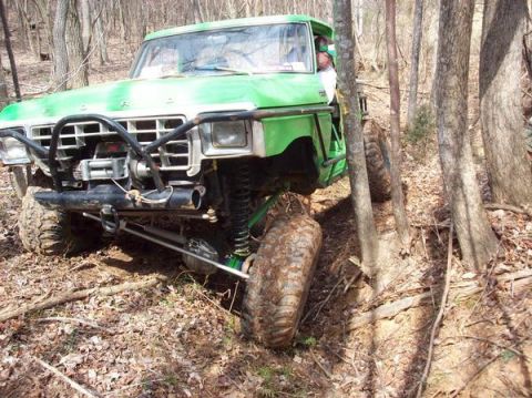 1978 Ford Bronco - A modified 1978 Ford Bronco tackles a challenging off-road path through a dense forest.