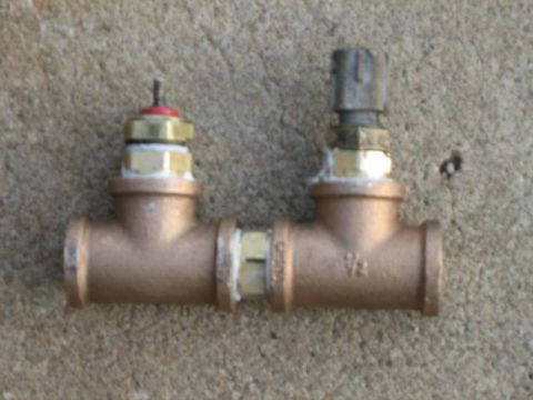 1996 Ford Thunderbird - Two brass valves are connected by a T-fitting, with one valve a red and gold cap and the other a gray cap. The fitting is marked with "1/2".