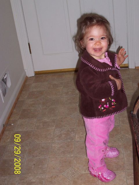 2000 Ford Crown Victoria - A young child smiles and waves while standing indoors.
