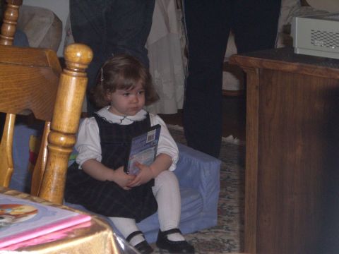 2000 Ford Crown Victoria - A young child sits indoors holding a DVD case, with furniture and adults in the background.