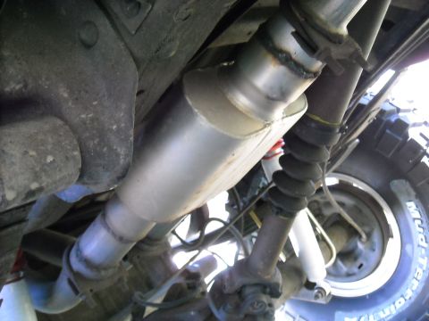 1994 Ford Bronco - Close-up of an exhaust system component, likely a muffler, on a vehicle's underside.