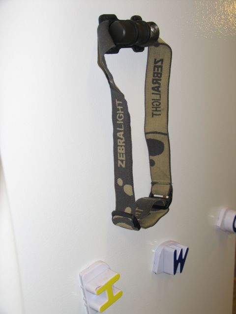 1984 Ford Bronco - A headlamp with a camouflage-patterned strap is attached to a white surface, with magnetic letters visible below.