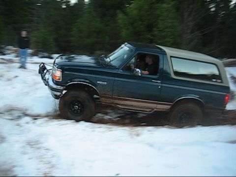 1995 Ford Bronco - A Ford Bronco navigates a snowy and muddy terrain.