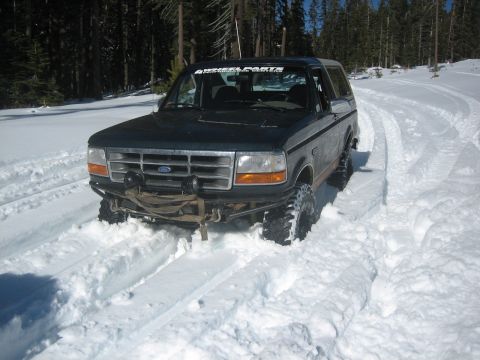 1995 Ford Bronco - This 1995 Ford Bronco is stuck in deep snow, showing its front end with an aftermarket bumper and off-road tires.