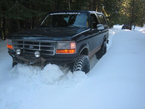 1995 Ford Bronco - Ford Bronco navigating deep snow on a winter trail, with another vehicle in the distance.