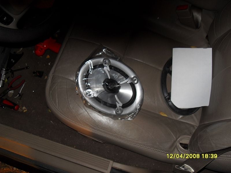 Car interior showing a car speaker on a leather seat, with tools on the floor