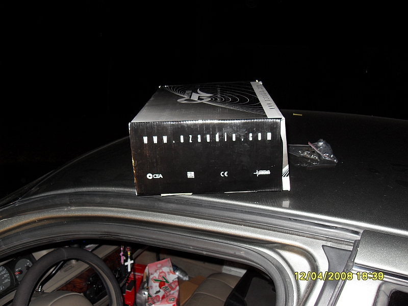 Cardboard box with www.ozaudio.com on the roof of a car, interior visible