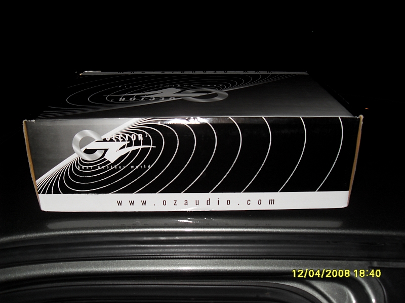 OZ Audio Protector amplifier box with logo and website on a dark surface.