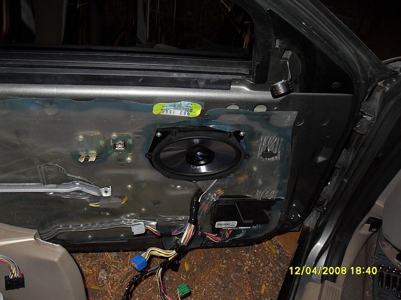 Car door interior panel removed, showing wiring and speaker mounting area