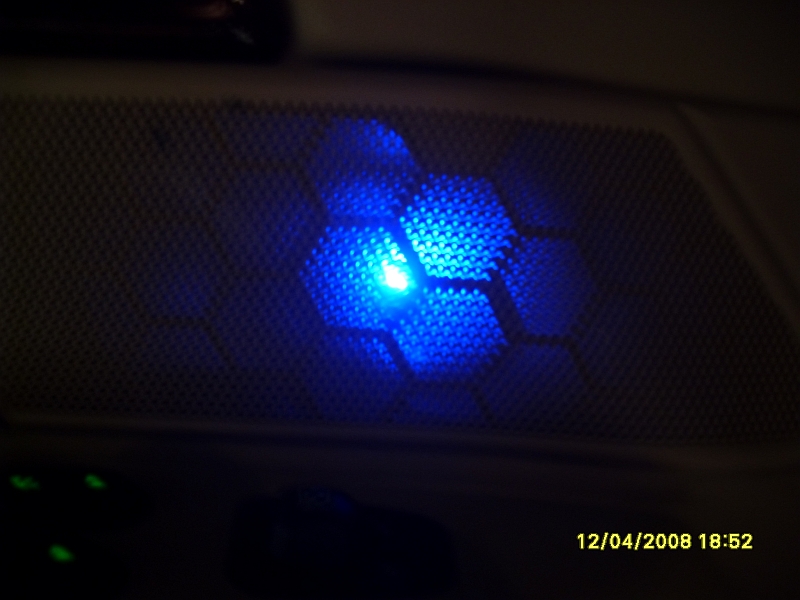 Car speaker grille with blue LED light and hexagonal pattern. Timestamp: 12/04/2008 18:52.