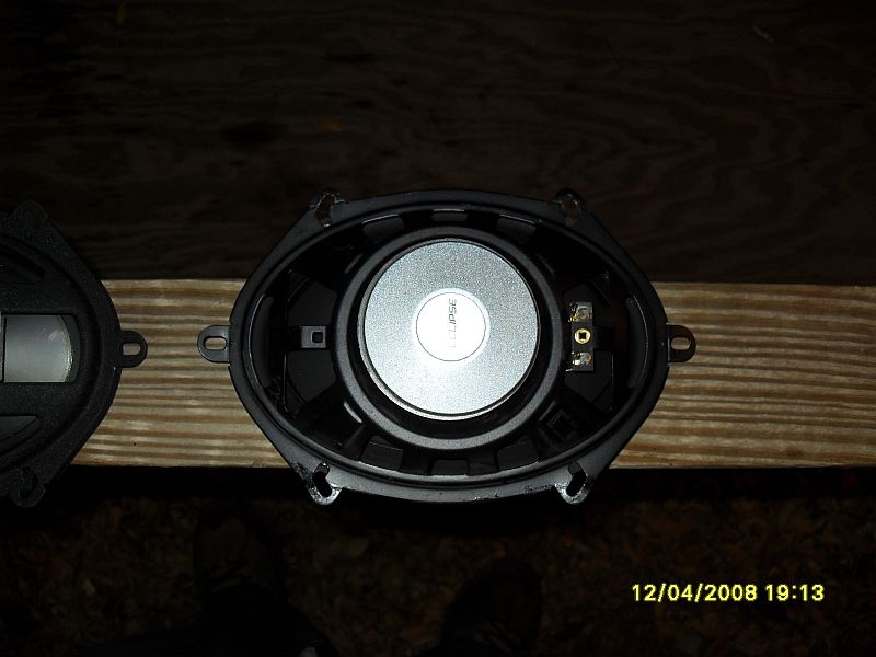 Two oval car speakers, one Eclipse brand, on a wooden surface.