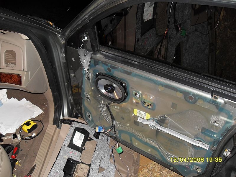 Interior view of a Mercury Marquis door with panel removed, showing speaker installation and tools.