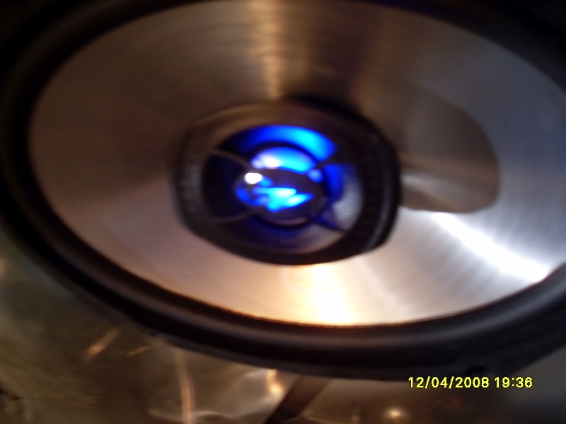 Car subwoofer with blue illuminated center, metallic cone, and black surround.