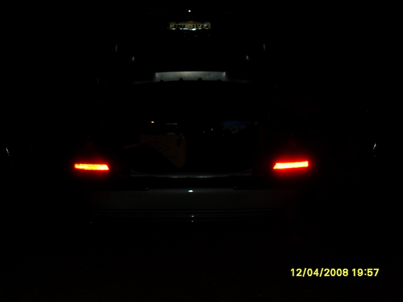 Rear view of a car at night with illuminated red brake lights.