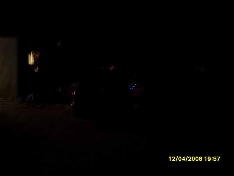 Blurry nighttime photo of a dark sedan with a date/time stamp.
