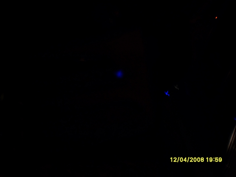 Darkness with timestamp "12/04/2008 19:59" and a few blurry blue and red lights.