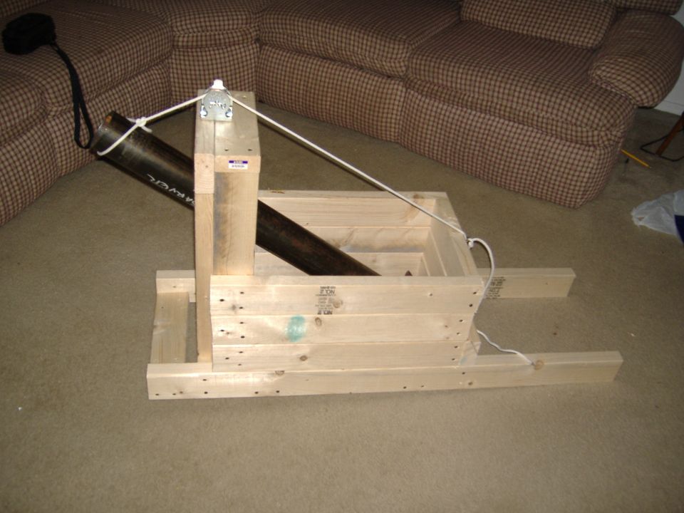 Wooden frame with metal pipe and rope on carpet, sofa in background
