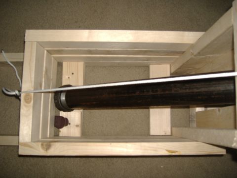 1988 Ford Bronco - A close-up overhead view of a dark-colored pipe secured within a wooden frame, with a white rope running across it. The pipe appears to be…