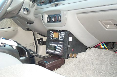 1991 Ford LTD Crown Victoria - Photograph of a police-car interior with floor/console-mounted radio gear and a microphone, not a technical document.
