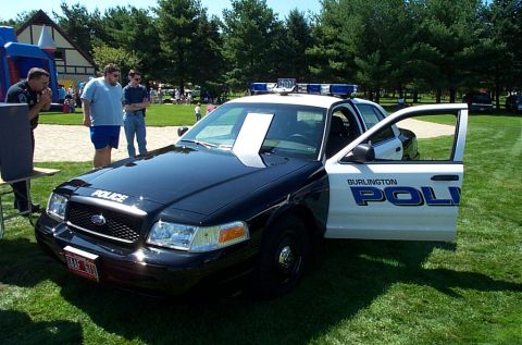 1991 Ford LTD Crown Victoria - Police car with doors open, parked on grass at an outdoor event.