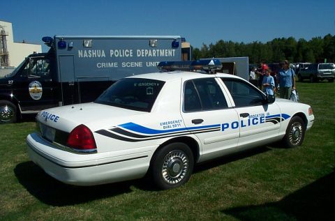 1991 Ford LTD Crown Victoria - Photograph of a Crown Victoria police cruiser beside a Nashua Police crime scene unit truck, not a technical document.