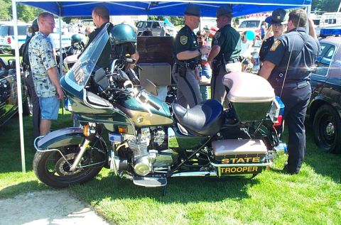 1991 Ford LTD Crown Victoria - Photograph of a State Trooper touring motorcycle displayed on grass with officers nearby.
