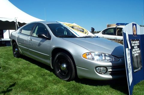 1991 Ford LTD Crown Victoria - Photograph of a silver Dodge Intrepid sedan parked beside an informational display board.