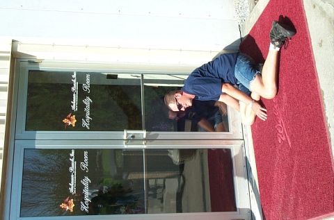 1991 Ford LTD Crown Victoria - Photograph of a man kneeling on a red welcome mat outside glass Hospitality Room doors.