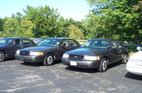 1991 Ford LTD Crown Victoria - Photograph of two unmarked black Ford Crown Victoria sedans parked in a paved lot.
