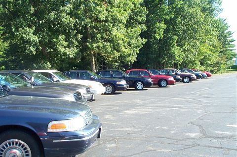 1991 Ford LTD Crown Victoria - Photograph of a line of parked Ford Crown Victoria and Mustang cars at an outdoor lot, not a technical document.