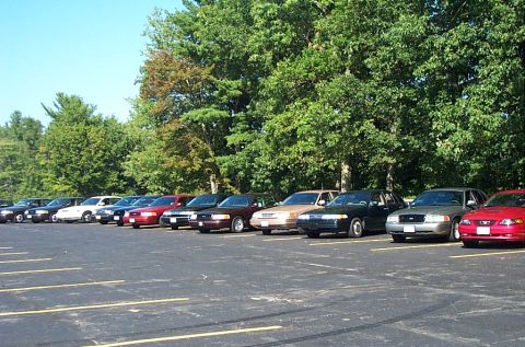1991 Ford LTD Crown Victoria - Photograph of numerous parked sedans in a large paved lot, not a technical document.