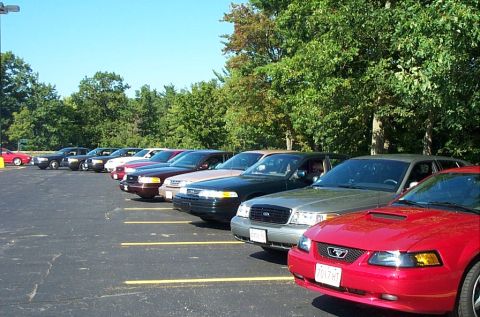 1991 Ford LTD Crown Victoria - Photograph of an angled row of parked cars led by a red Mustang, not a technical document.