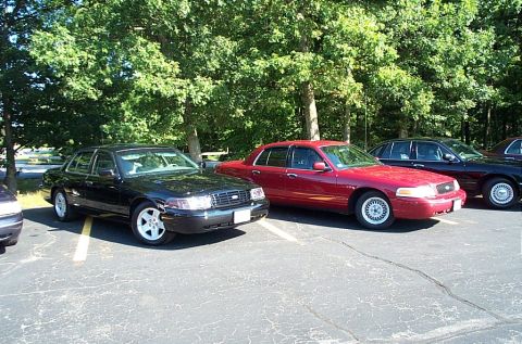1991 Ford LTD Crown Victoria - Photograph of a black and a red parked sedan in a lot, not a technical document.