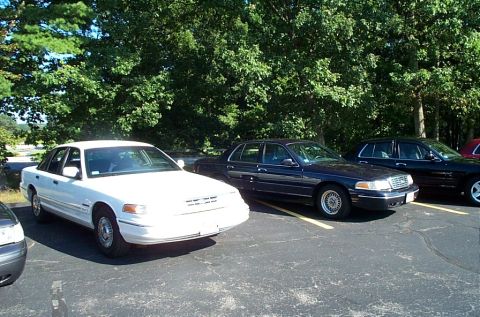 1991 Ford LTD Crown Victoria - Photograph of a white sedan parked among dark sedans, not a technical document.