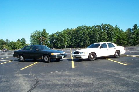 1991 Ford LTD Crown Victoria - Photograph of a green and a white sedan facing each other, not a technical document.