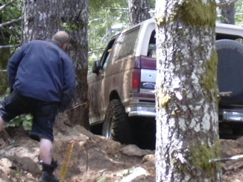 1991 Ford Bronco - A 1991 Ford Bronco maneuvers through a challenging off-road course surrounded by trees and rough terrain.