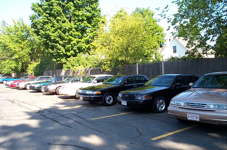 Line of parked sedans in a paved lot