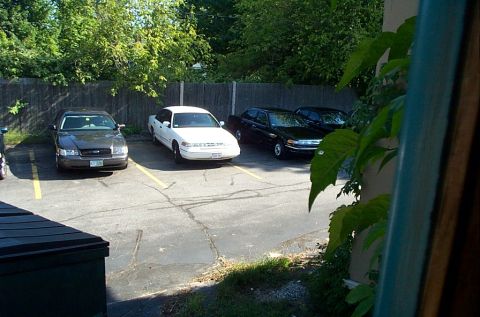 1991 Ford LTD Crown Victoria - Several cars are parked in a lot, including a dark gray Ford Crown Victoria.