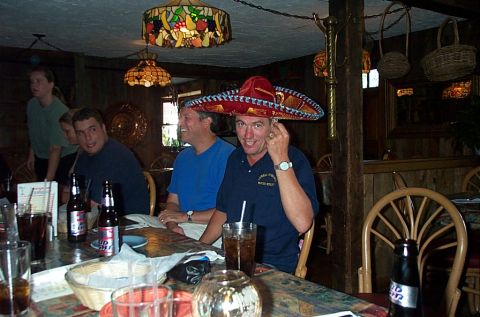 1991 Ford LTD Crown Victoria - Men enjoy drinks and conversation at a table in a restaurant, with one man playfully wearing a sombrero.