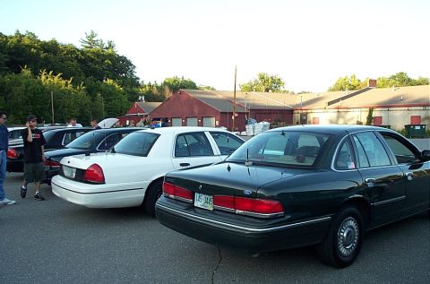 1991 Ford LTD Crown Victoria - Several Ford Crown Victoria sedans are parked in a lot with a red building in the background.