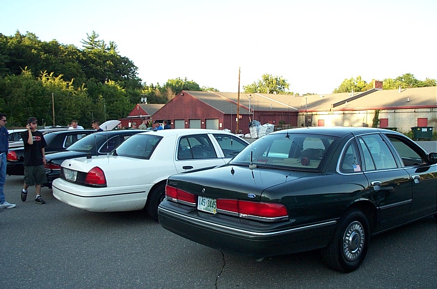 Dark green Ford Crown Victoria sedan parked, showing rear quarter panel, taillights, and license plate