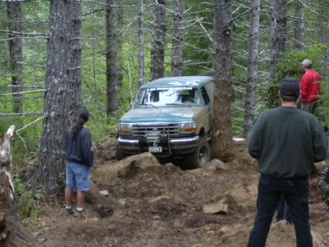 1991 Ford Bronco - A Ford Bronco navigates a challenging off-road course in a wooded area.