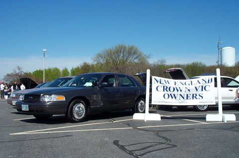 1991 Ford LTD Crown Victoria - Two Ford Crown Victorias at a car meet, one dark gray and one white, with a club banner.