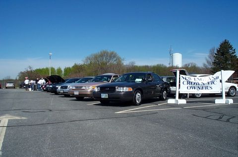 1991 Ford LTD Crown Victoria - A gathering of Ford Crown Victoria owners is shown with several vehicles lined up in a parking lot under a clear blue sky.